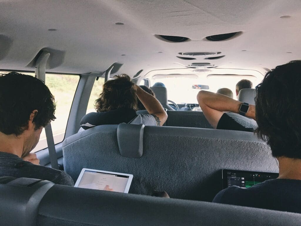 A group of people riding together on a long trip in a 10 passenger van trying to stay entertained.